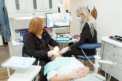 dentist and assistant helping patient in chair