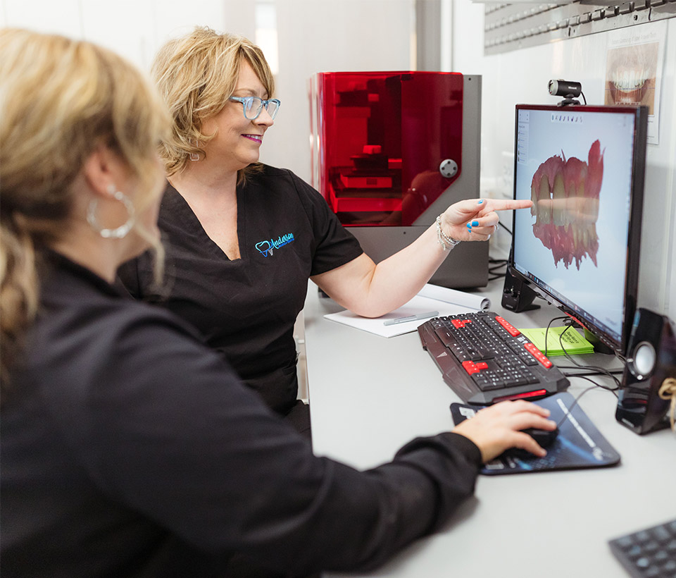 Two staff members looking at a 3D image scan of a patient's mouth